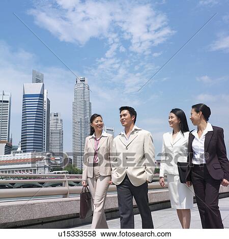 Stock Photo - Low angle view of a businessman walking with three businesswomen. Fotosearch