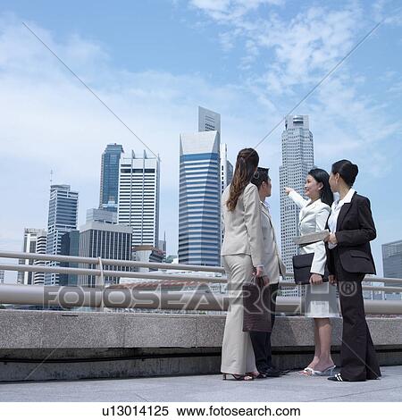 Stock Photography - Low angle view of a businesswoman pointing towards buildings. Fotosearch