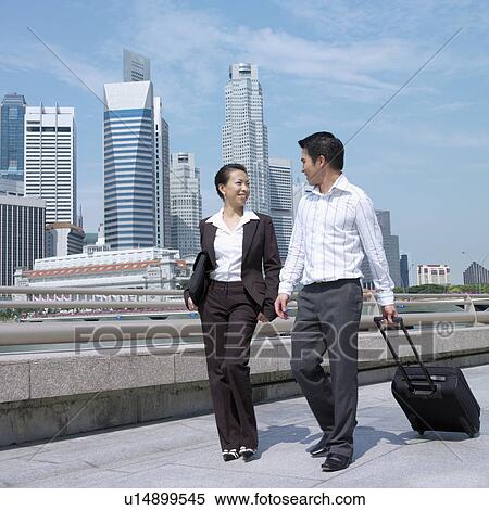 Low angle view of a businesswoman talking to a businessman and pulling a suitcase View Large Photo Image Stock Photography - Low angle view of a businesswoman talking to a businessman and pulling a suitcase. Fotosearch