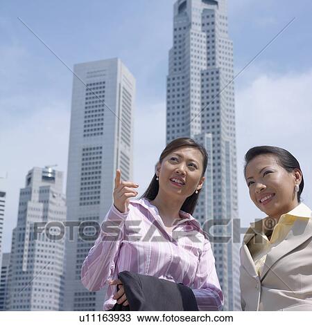 Low angle view of two businesswomen smiling in front of buildings View Large Photo Image Stock Image - Low angle view of two businesswomen smiling in front of buildings. Fotosearch
