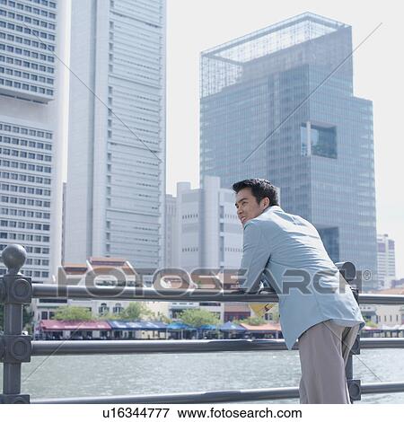 Stock Photo - Rear view of a businessman leaning over a railing. Fotosearch
