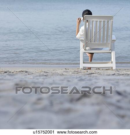 Rear view of a young woman talking on a mobile phone at the beach View Large Photo Image Stock Image - Rear view of a young woman talking on a mobile phone at the beach. Fotosearch