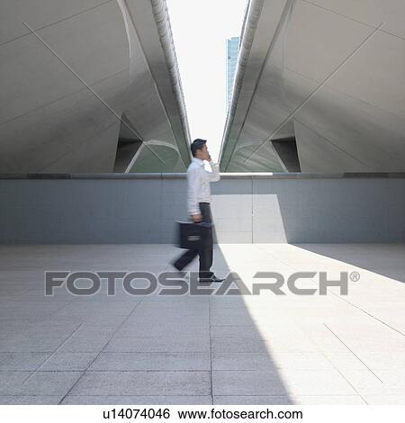 Stock Photograph - Side profile of a businessman talking on a mobile phone. Fotosearch