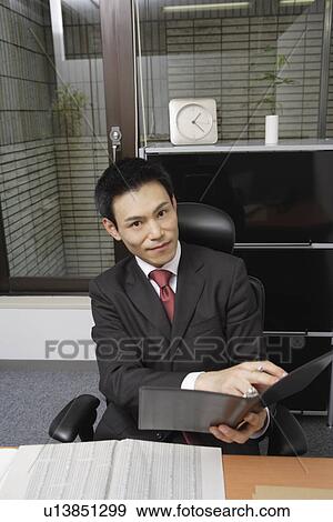 Businessman browsing a file, portrait View Large Photo Image Stock Photo - Businessman browsing a file, portrait. Fotosearch