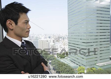 Stock Image - Businessman looking out through a window, portrait. Fotosearch