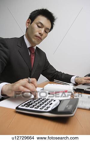 Picture - Businessman using a calculator, portrait. Fotosearch