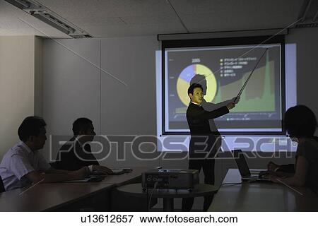 Stock Photo - Businessman with a graphical representation at a conference. Fotosearch