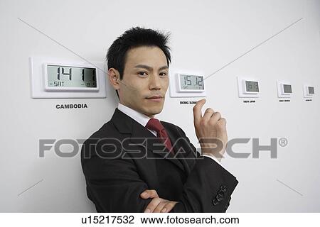 Stock Image - Businessman with time zones, portrait. Fotosearch
