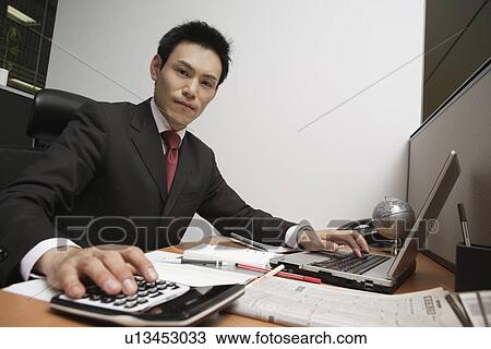 Stock Image - Businessman working at his desk, portrait. Fotosearch