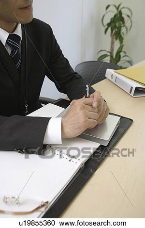 Cropped view of a man sitting at his desk View Large Photo Image Stock Image - Cropped view of a man sitting at his desk. Fotosearch