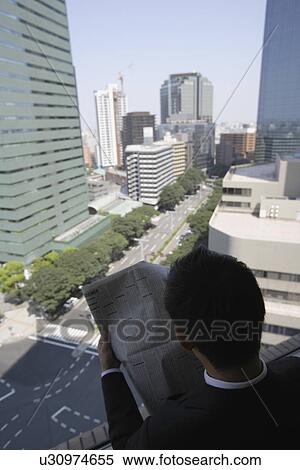 Stock Photography - High angle view of a businessman reading a newspaper. Fotosearch