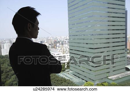 Picture - View of a businessman looking out through a window. Fotosearch