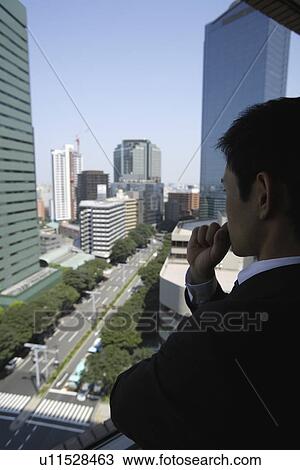 Stock Image - View of a businessman looking out through a window. Fotosearch