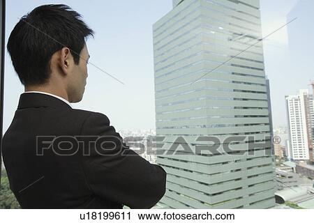 Stock Image - View of a businessman looking out through a window. Fotosearch