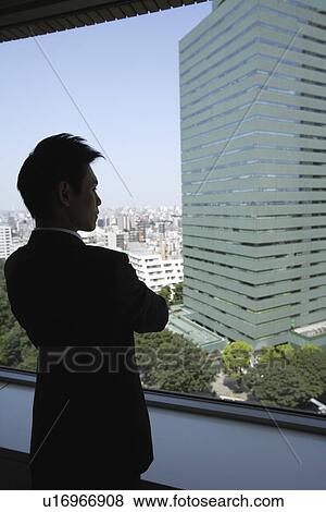 Stock Photo - View of a businessman looking out through a window. Fotosearch