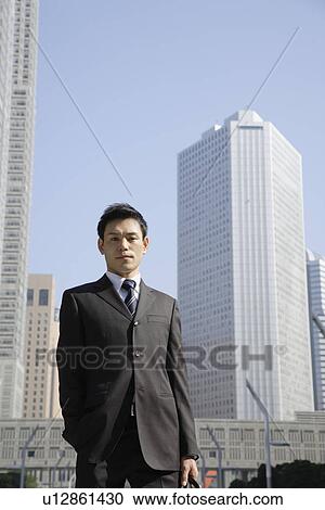 Stock Image - Businessman against office buildings, portrait. Fotosearch