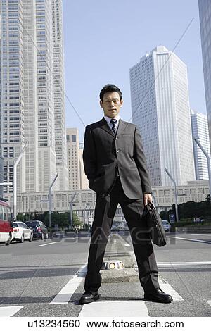 Stock Image - Businessman amid office buildings. Fotosearch