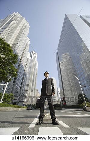 Stock Photograph - Businessman amid office buildings. Fotosearch