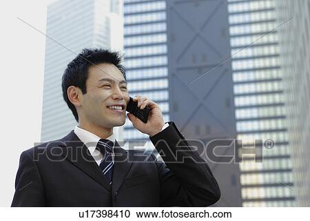 Stock Image - Businessman conversing on his cellphone, portrait. Fotosearch