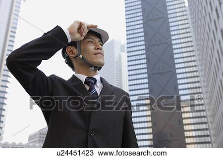 Stock Image - Businessman holding his hard hat, portrait. Fotosearch