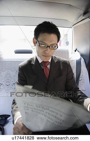 Stock Photo - Businessman reading newspaper in car, portrait. Fotosearch
