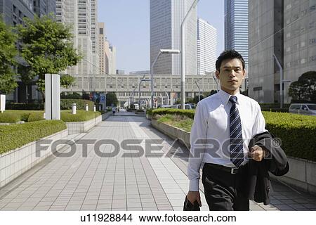 Picture - Businessman walking on a sidewalk. Fotosearch