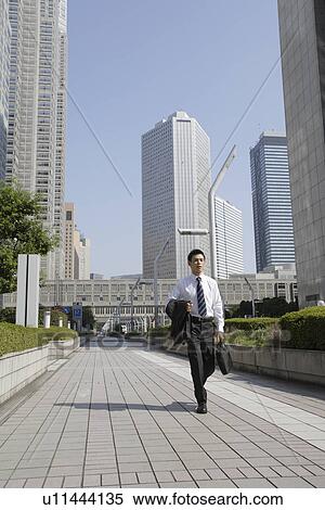 Stock Photography - Businessman walking on a sidewalk. Fotosearch