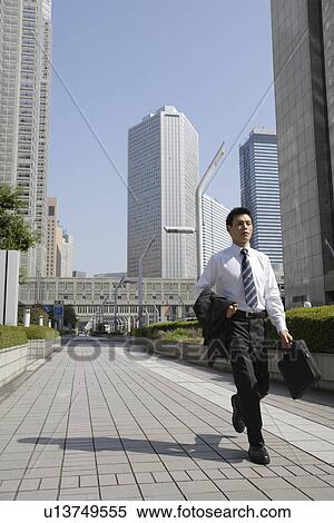 Businessman walking on a sidewalk View Large Photo Image Stock Photography - Businessman walking on a sidewalk. Fotosearch