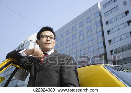 Stock Photo - Man leaning against car door, portrait. Fotosearch