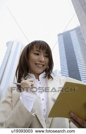 Businesswoman holding a book and a pen, portrait View Large Photo Image Stock Image - Businesswoman holding a book and a pen, portrait. Fotosearch