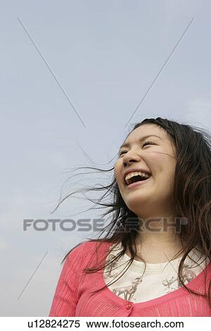 A young woman is seen under the sky as she laughs her way to glory View Large Photo Image Stock Photography - A young woman is seen under the sky as she laughs her way to glory. Fotosearch