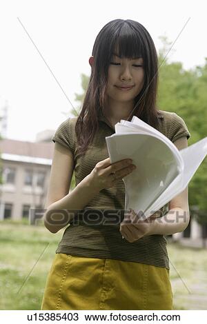 Stock Image - A young woman smiles as she goes through the files and papers. Fotosearch