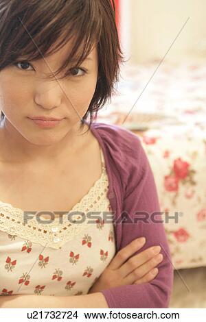 a young woman staring up, with her arms crossed View Large Photo Image Picture - a young woman staring up, with her arms crossed. Fotosearch