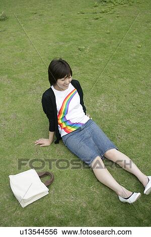 Stock Photograph - High angle view of a young woman relaxing on the grassland. Fotosearch