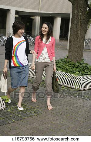Stock Photograph - Two young women walking side-by-side. Fotosearch
