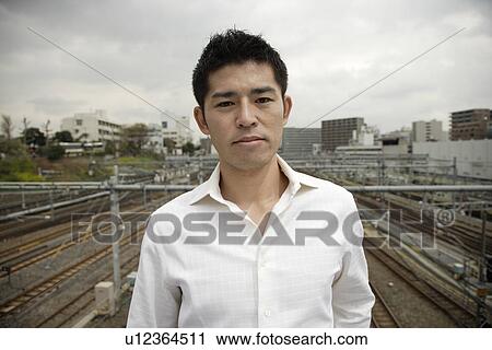 A young man standing with railroad tracks in background View Large Photo Image Stock Image - A young man standing with railroad tracks in background. Fotosearch