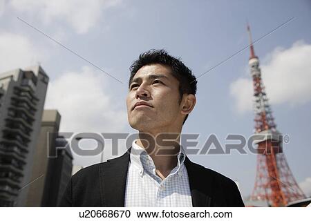 Stock Image - Low angle view of a young man looking away. Fotosearch