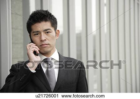 Stock Image - Portrait of a young businessman using mobile phone. Fotosearch