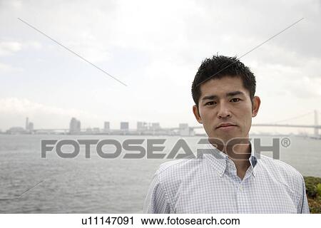 Stock Image - Portrait of a young man with sea in background. Fotosearch
