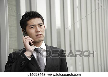Stock Photo - View of a young businessman using mobile phone. Fotosearch