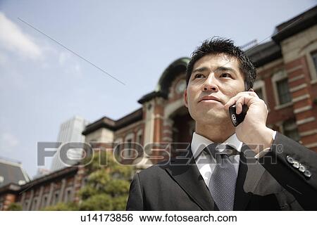 Stock Photograph - View of a young businessman using mobile phone. Fotosearch