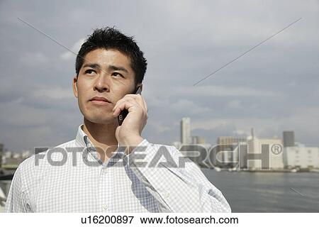 Stock Photo - View of a young man using mobile phone. Fotosearch