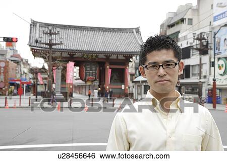 Young man standing outside temple View Large Photo Image Stock Photograph - Young man standing outside temple. Fotosearch