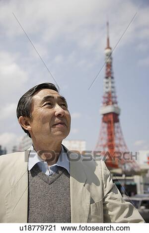 Stock Image - Senior man standing with tower in background. Fotosearch