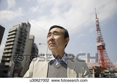 Stock Image - Senior man standing with tower in background. Fotosearch