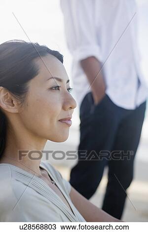 Stock Image - A woman looking away with man in background. Fotosearch