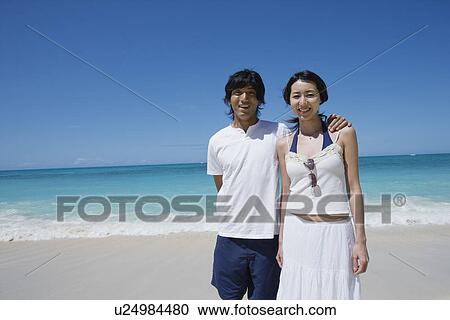 Stock Image - A young couple standing on beach. Fotosearch