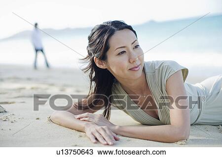 A young woman lying on sand at beach View Large Photo Image Stock Image - A young woman lying on sand at beach. Fotosearch
