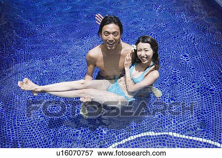 Stock Photo - Elevated view of a couple in swimming pool. Fotosearch