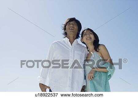 Stock Photo - Low angle view of young couple smiling. Fotosearch